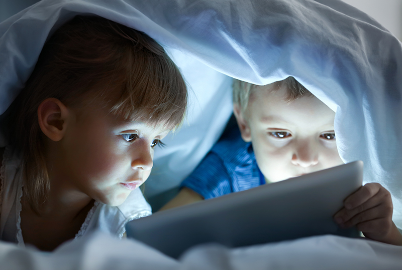 children with screen under sheets